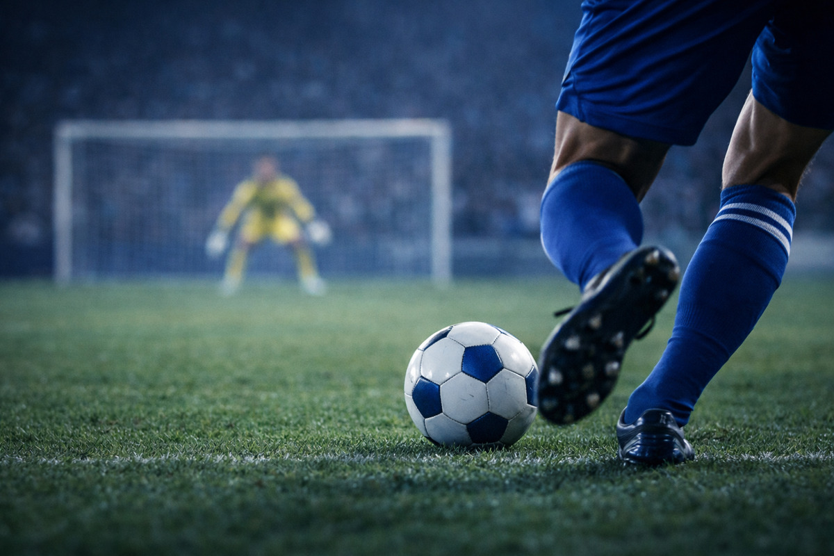 PKを蹴ろうとするキッカーの足元を手前に、ゴール前で構えるキーパーを奥にぼかして捉えた対峙の瞬間