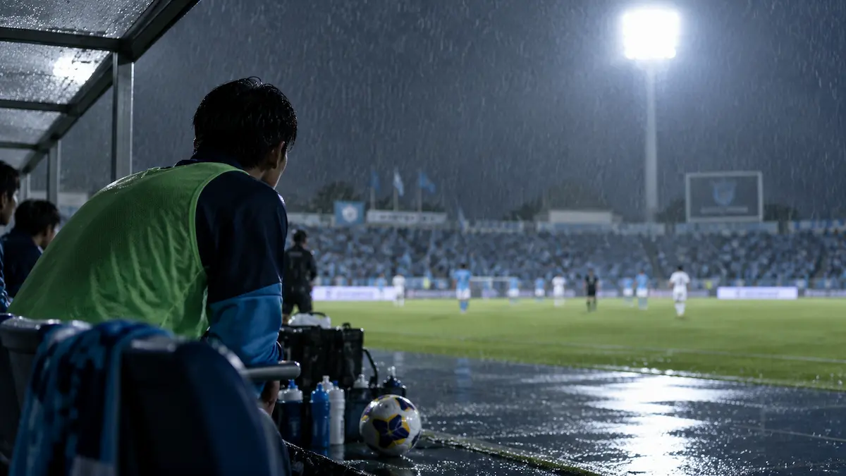 雨の三ツ沢でピッチを見つめながら出番を待つ横浜FCの選手